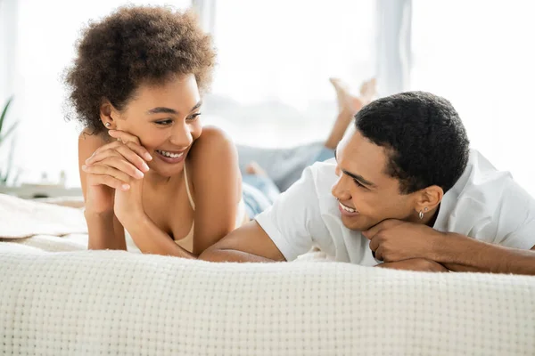 Joyeux couple afro-américain se regardant sur le lit à la maison — Photo de stock