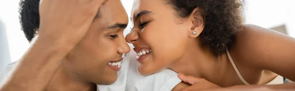 Mujer afroamericana emocionada sonriendo cara a cara con novio joven y feliz, pancarta - foto de stock