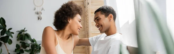 Cheerful african american couple smiling at each other at home on blurred foreground, banner — Stock Photo
