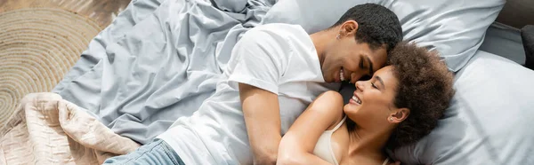 Vista dall'alto di allegri amanti afroamericani che si rilassano sul letto a casa, banner — Foto stock
