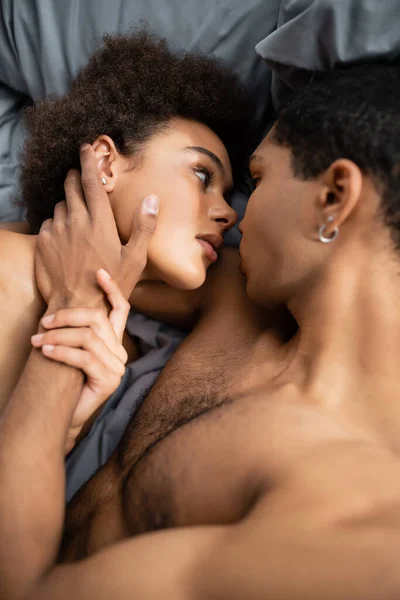 Vue de dessus de l'homme américain africain torse nu touchant le visage de la petite amie séduisante — Stock Photo