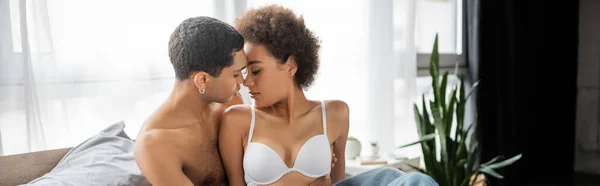 Morena rizada mujer afroamericana en sujetador blanco cerca de novio sin camisa y sexy, pancarta — Stock Photo