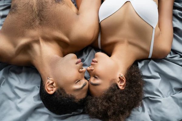 Вид зверху без сорочки афроамериканський чоловік і жінка в бюстгальтері лежить обличчям до обличчя із закритими очима — Stock Photo