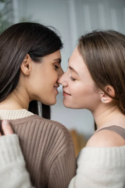 Seitenansicht eines gleichgeschlechtlichen Paares, das in der Küche lächelt und sich küsst — Stockfoto