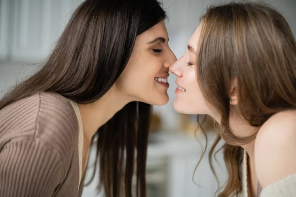 Side view of positive lesbians kissing in kitchen — Stock Photo