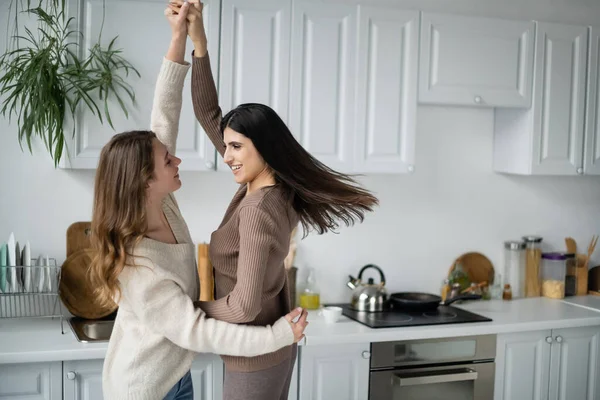 Позитивная лесбийская пара танцует дома на кухне — стоковое фото