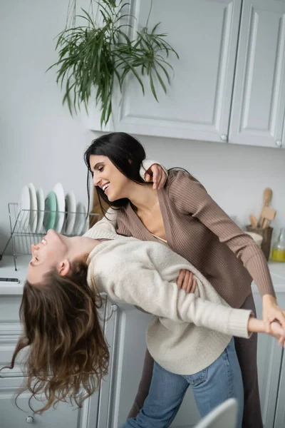 Side view of lesbian couple dancing and laughing in kitchen — Stock Photo