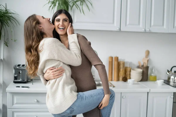 Cheerful same sex couple dancing and laughing in kitchen — Stock Photo