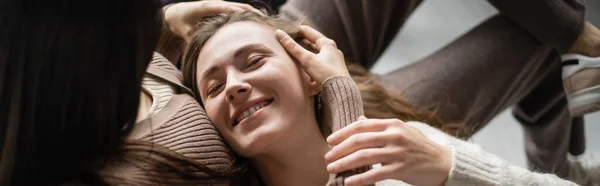 Vue grand angle de la femme touchant partenaire souriant sur le canapé à la maison, bannière — Photo de stock