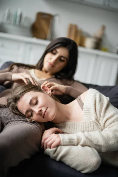 Blurred lesbiana mujer tocando novia en suéter en sofá - foto de stock