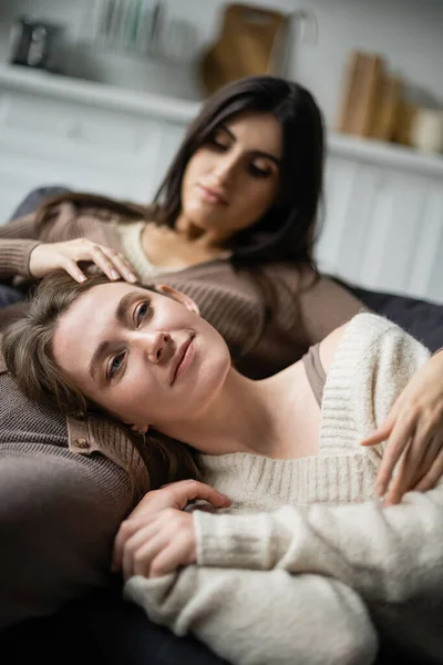 Молодая женщина трогает лесбиянку в свитере на диване — стоковое фото
