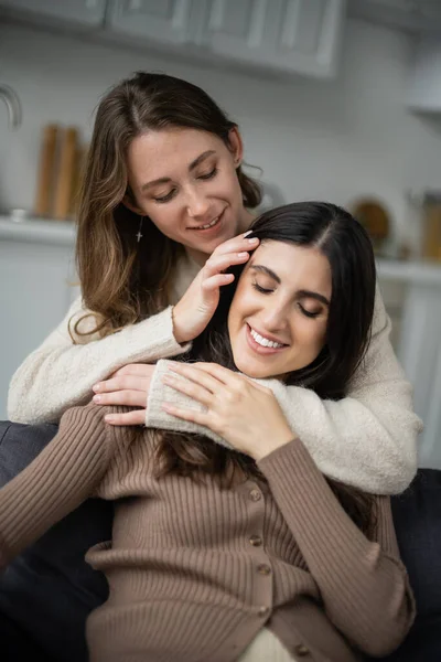 Young lesbian woman touching brunette girlfriend on couch — Stock Photo