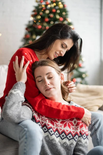 Positive lesbian couple touching each other during new year celebration at home — Stock Photo