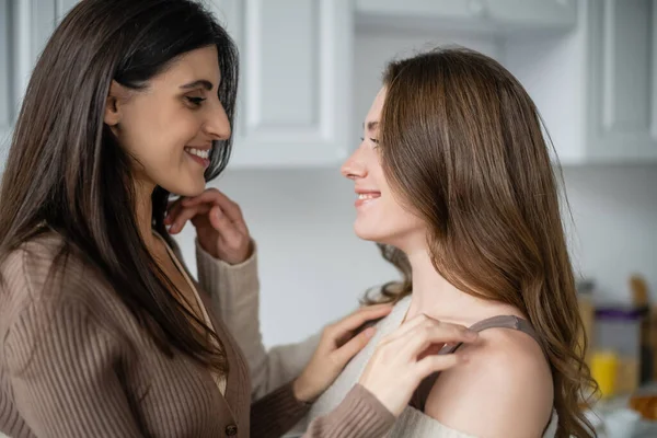 Side view of smiling lesbian couple touching each other in kitchen — Stock Photo