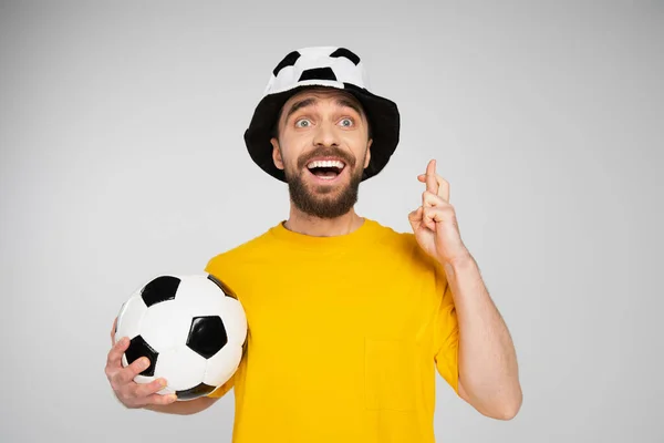 Чудовий футбольний вентилятор з відкритим ротом, тримаючи схрещені пальці ізольовані на сірому — стокове фото
