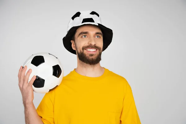 Веселий бородатий фанат футболу тримає футбольний м'яч і дивиться ізольовано на сірий — стокове фото
