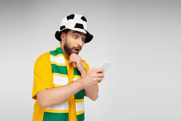 Thrilled sports fan watching football championship on smartphone isolated on grey — Stock Photo