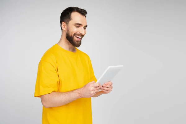 Homem barbudo alegre olhando para tablet digital isolado em cinza — Fotografia de Stock
