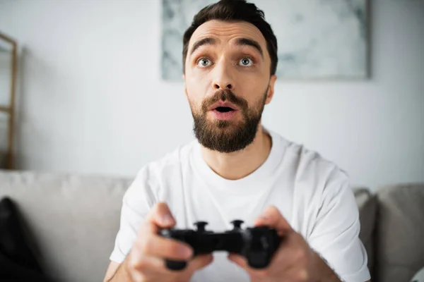 KYIV, UKRAINE - OCTOBER 21, 2022: focused and bearded man holding joystick and playing video game — Stock Photo