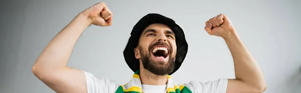 Бородатий чоловік у спортивному капелюсі та шарфі радіє під час чемпіонату, банер — стокове фото
