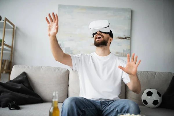 QUIIV, UCRÂNIA - OUTUBRO 21, 2022: homem animado em vr headset gesticulando na sala de estar — Fotografia de Stock