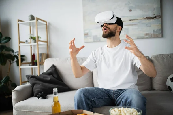 KYIV, UKRAINE - OCTOBER 21, 2022: stunned bearded man in vr headset gesturing while gaming in home — Stock Photo