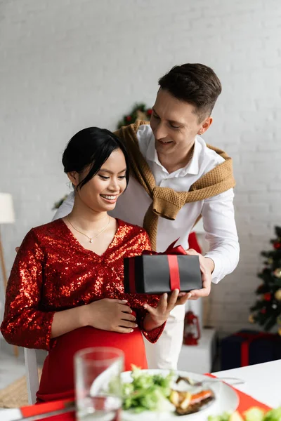 Giovane marito regalo di Natale per la moglie asiatica incinta ed elegante — Foto stock