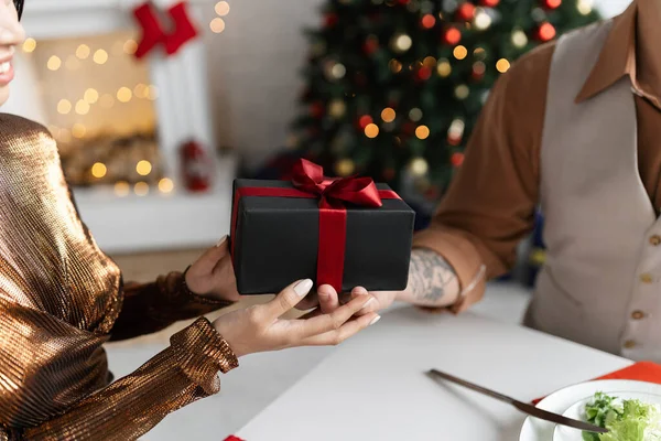 Cropped view of smiling woman in shiny blouse taking Christmas gift from husband — Stock Photo
