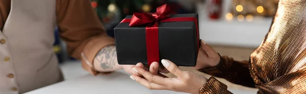 Обрізаний вид чоловіка, який тримає різдвяний подарунок біля дружини вдома, банер — стокове фото