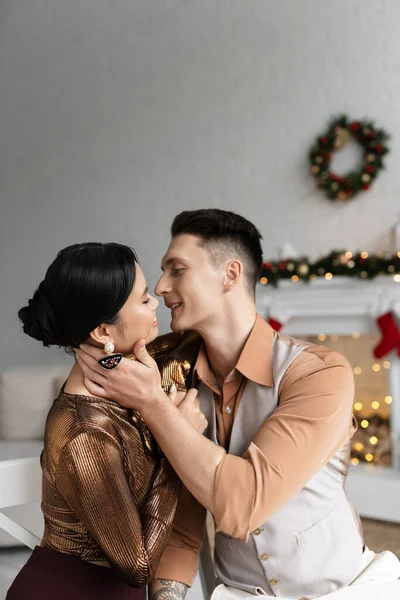 Giovane coppia interrazziale in abiti eleganti che si abbracciano durante la celebrazione del Natale a casa — Foto stock