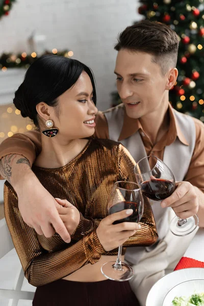 Elegant multiethnic couple clinking wine glasses during festive romantic supper at home — Stock Photo