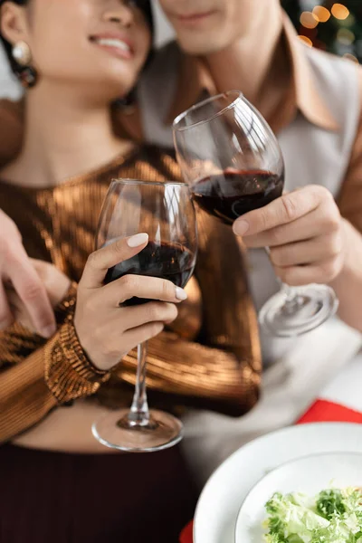 Cropped view of blurred couple clinking wine glasses while celebrating Christmas at home — Stock Photo