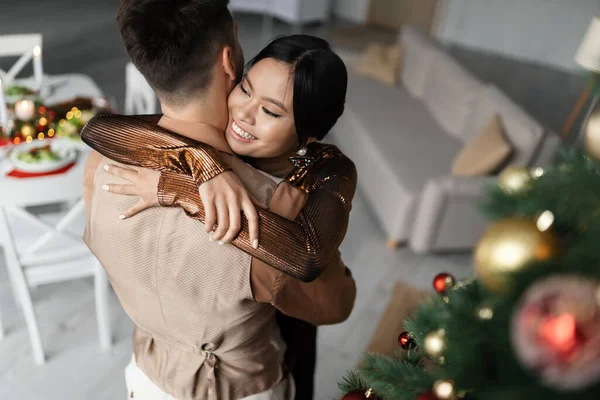 High angle view of cheerful asian woman hugging husband during Christmas celebration — Stock Photo
