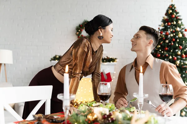 Щаслива міжрасова пара дивиться один на одного біля святкової їжі на Різдво — стокове фото