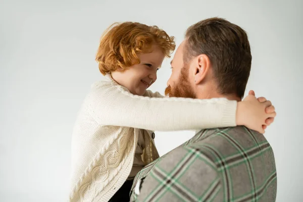 Lächelnder rothaariger Junge im warmen Pullover umarmt Papa isoliert auf grau — Stockfoto