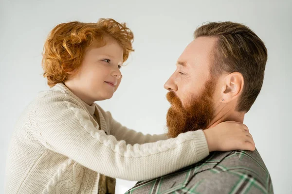Souriant enfant roux étreignant père barbu en veste isolé sur gris — Photo de stock