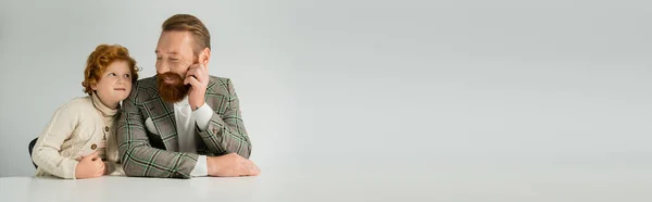Garçon roux en pull tricoté regardant le parent barbu isolé sur gris, bannière — Photo de stock