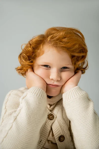 Ritratto di ragazzo dai capelli rossi annoiato in maglione lavorato a maglia che guarda la macchina fotografica isolata su grigio — Foto stock