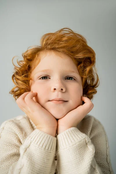 Redhead boy in warm beige jumper looking at camera isolated on grey — Stock Photo