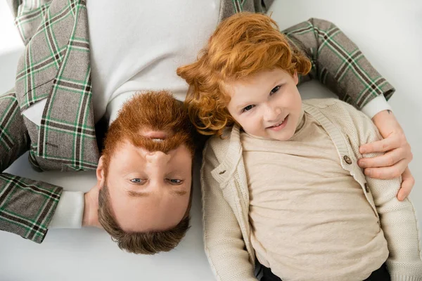 Draufsicht des rothaarigen Vaters und Sohnes in stylischer Kleidung auf grauem Hintergrund — Stockfoto