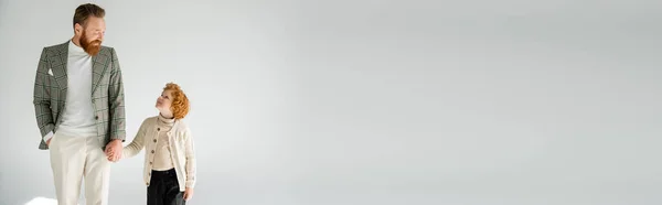 Homme barbu à la mode avec fils roux tenant la main et se regardant sur fond gris, bannière — Photo de stock