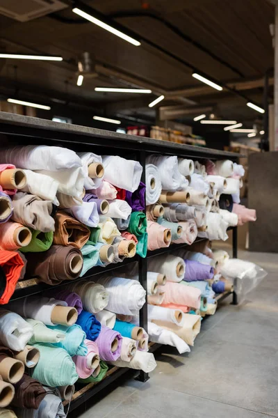 Surtido de diferentes rollos de tela en estantes en la tienda textil — Stock Photo