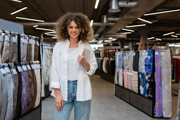 Весела продавчиня тримає цифровий планшет біля різної тканини в текстильному магазині — стокове фото