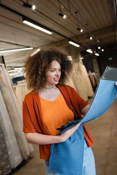Cliente sonriente mirando muestras de tela en tienda textil - foto de stock