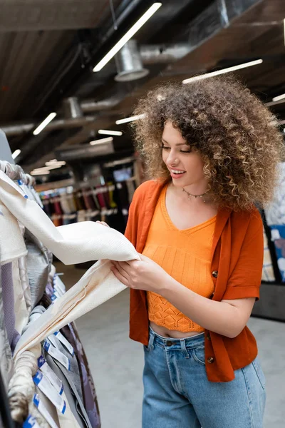 Positive client touching fabric in blurred textile shop — Stock Photo
