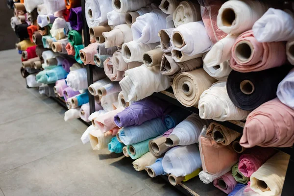 Colorful fabric rolls on shelves in textile shop — Stock Photo