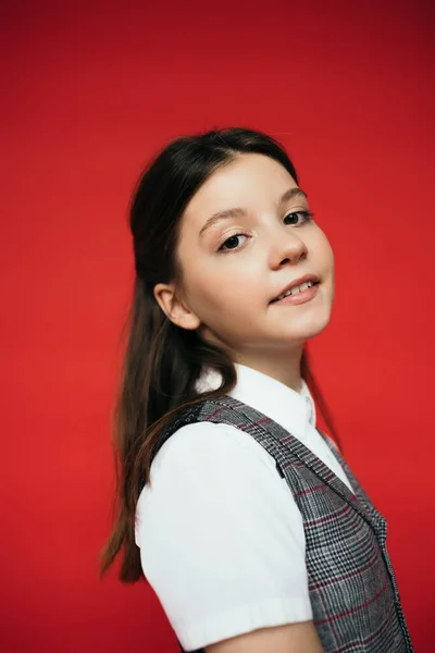 Portrait of preteen girl in white blouse and plaid vest smiling at camera isolated on red, banner — Stock Photo