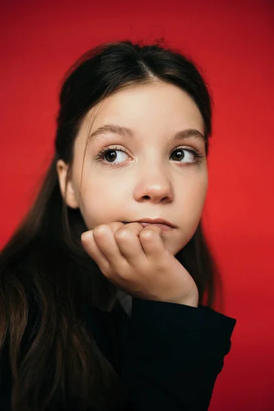 Портрет вдумчивой девочки-подростка с длинными волосами, смотрящей вдаль изолированной на красный — стоковое фото