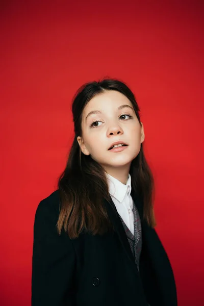 Porträt eines brünetten Mädchens in schwarzem Blazer, das isoliert auf Rot wegschaut — Stockfoto