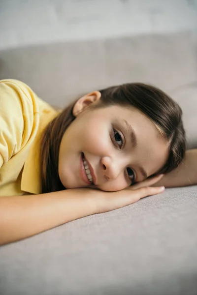 Щаслива дівчина лежить на м'якому дивані і дивиться на камеру — стокове фото